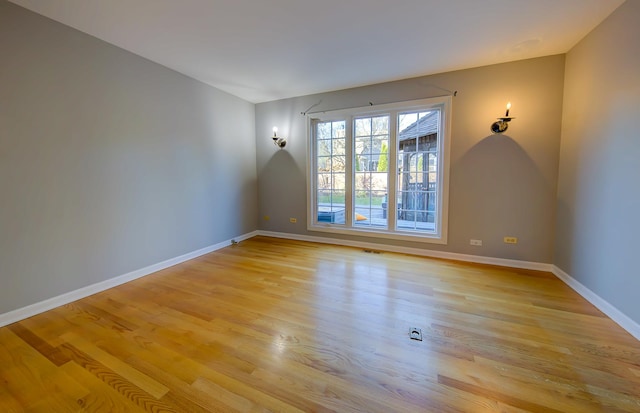 empty room with baseboards, visible vents, and light wood finished floors