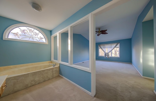 interior space with lofted ceiling, ceiling fan, baseboards, and a bath