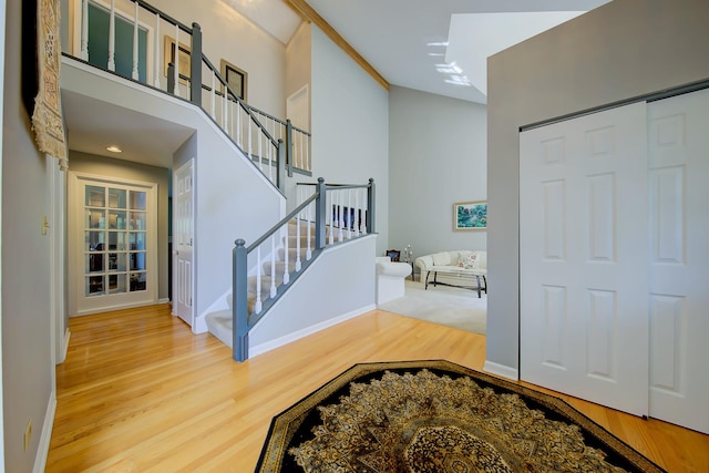 foyer entrance featuring stairs, a high ceiling, wood finished floors, and baseboards