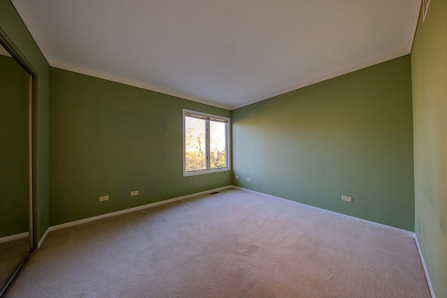 carpeted spare room featuring visible vents, crown molding, and baseboards