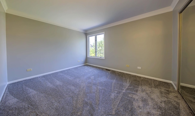 carpeted spare room featuring baseboards and crown molding