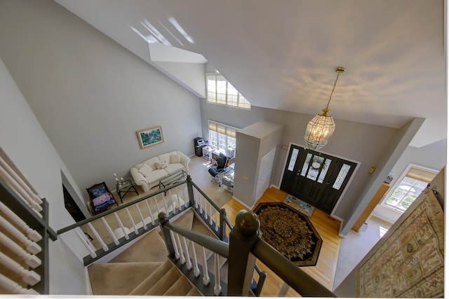 foyer with a chandelier, high vaulted ceiling, and wood finished floors