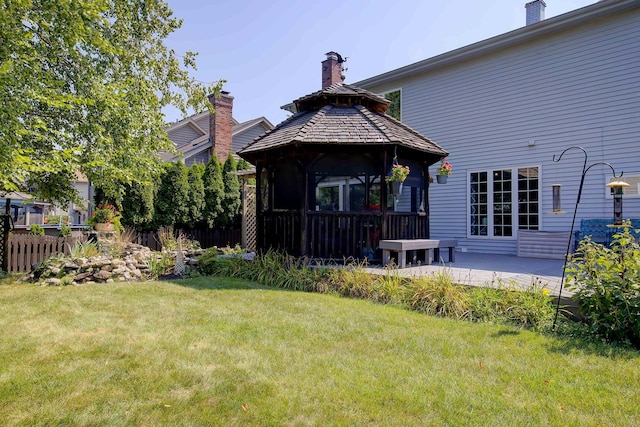 back of property featuring a yard, a chimney, a gazebo, a patio area, and fence