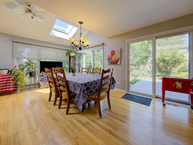 dining room featuring light wood-style floors, baseboards, a chandelier, and lofted ceiling with skylight