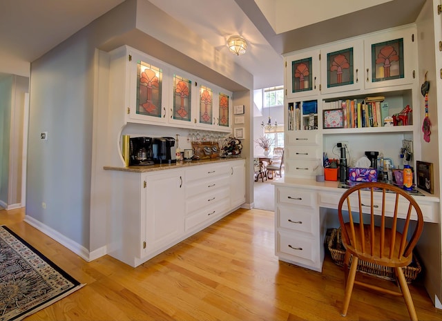 office area featuring built in study area, light wood-style flooring, and baseboards