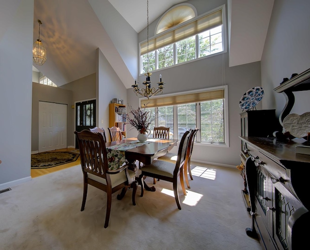 dining space featuring an inviting chandelier, carpet, high vaulted ceiling, and baseboards