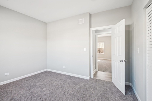 carpeted empty room featuring visible vents and baseboards