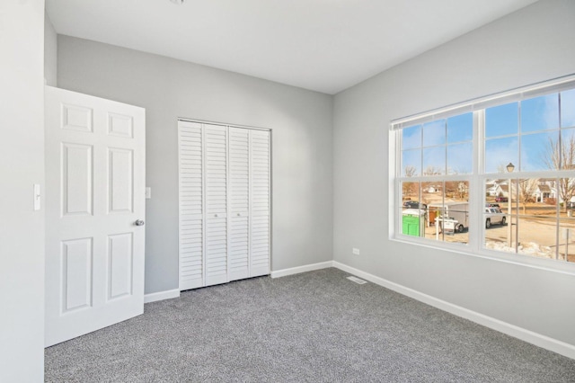 unfurnished bedroom with carpet floors, a closet, visible vents, and baseboards