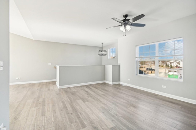 spare room featuring light wood-style flooring, baseboards, and ceiling fan with notable chandelier