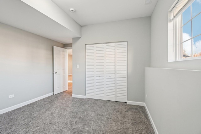 unfurnished bedroom featuring baseboards, a closet, and carpet flooring