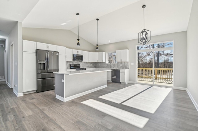 kitchen with stainless steel appliances, a kitchen island, white cabinets, and decorative backsplash