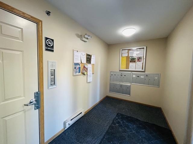 hallway featuring mail area and baseboard heating