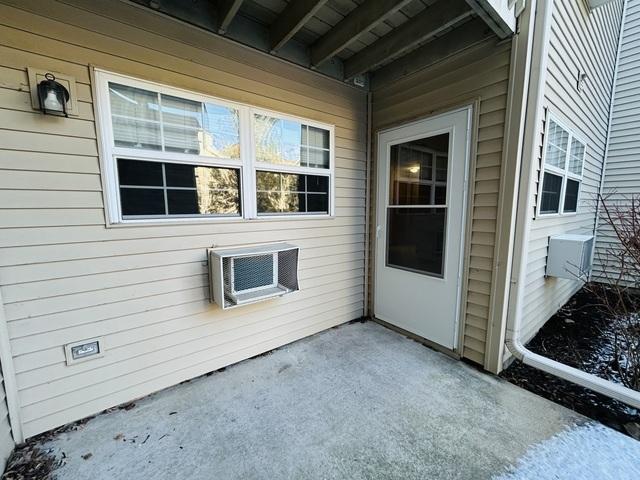 doorway to property with a patio and a wall unit AC