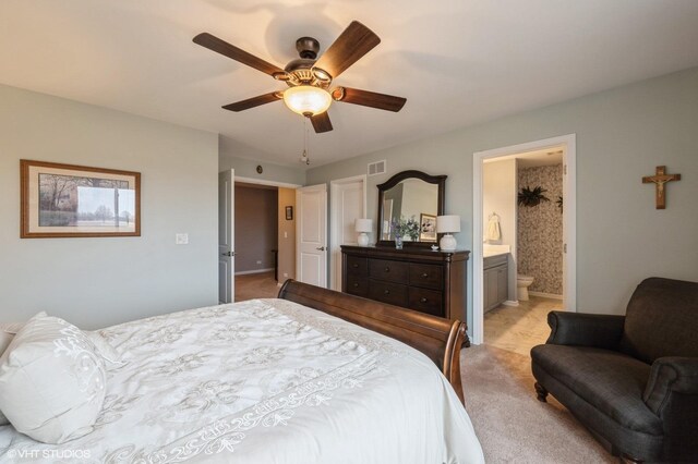 bedroom featuring light carpet, ensuite bath, visible vents, and ceiling fan