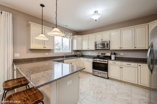 kitchen with marble finish floor, a breakfast bar area, appliances with stainless steel finishes, a sink, and a peninsula