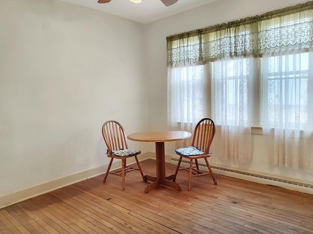 dining area featuring ceiling fan, light wood finished floors, baseboard heating, and baseboards