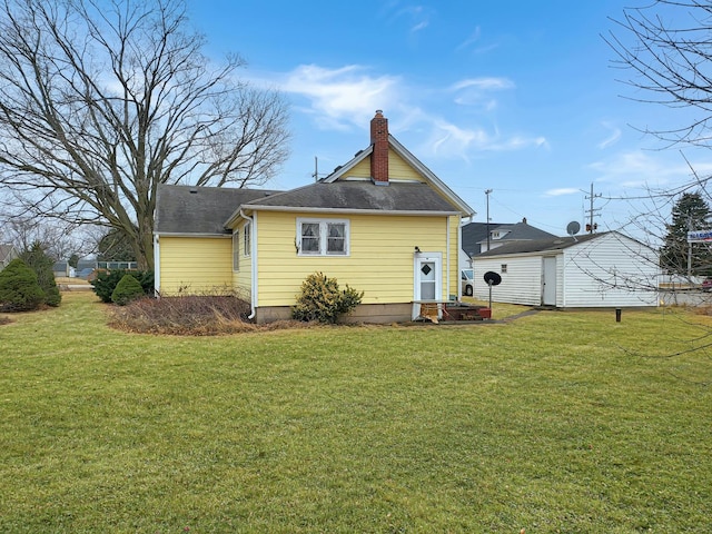 rear view of house featuring roof with shingles, a lawn, and a chimney