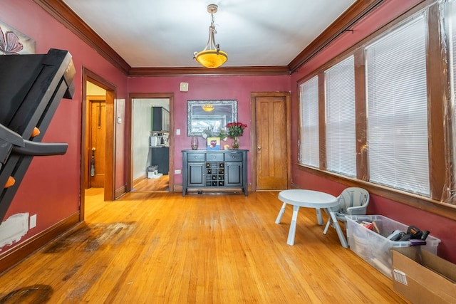 dining area featuring wood-type flooring, crown molding, and baseboards