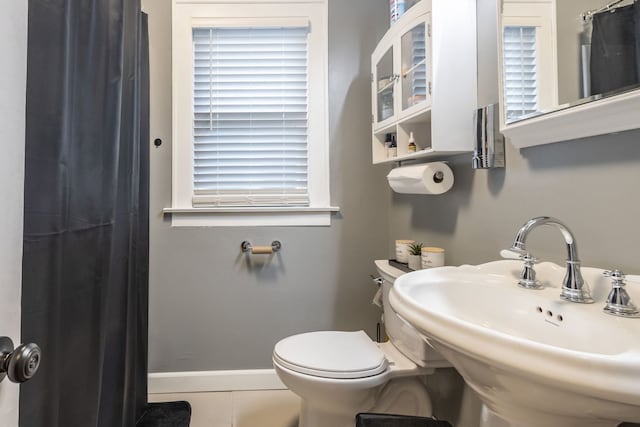 full bath with baseboards, toilet, a shower with curtain, tile patterned flooring, and a sink