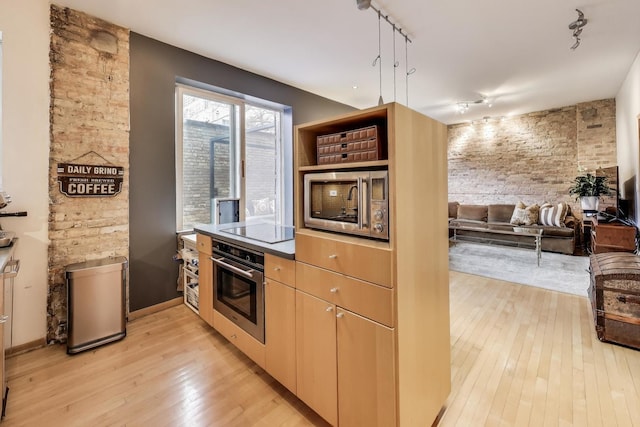 kitchen with open floor plan, appliances with stainless steel finishes, track lighting, and light wood-style floors