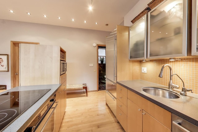 kitchen featuring built in appliances, recessed lighting, a sink, light wood-type flooring, and decorative backsplash