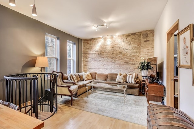 living room with brick wall, track lighting, and wood finished floors