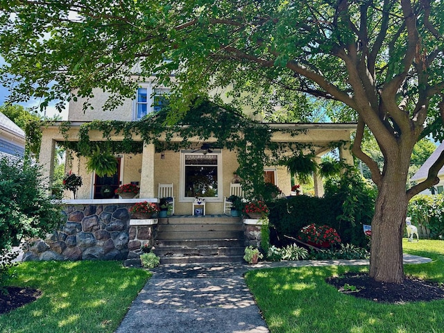 bungalow-style home with a porch, stucco siding, and a front yard