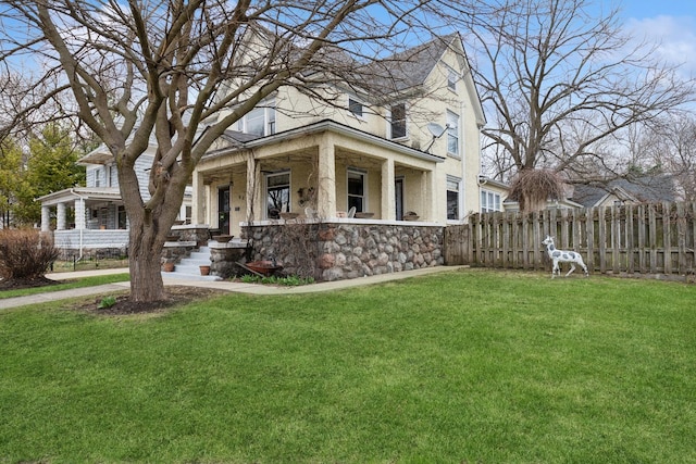 view of front facade with stucco siding, stone siding, a front yard, a porch, and fence