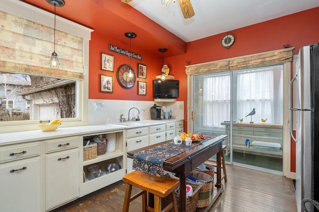 kitchen featuring dark wood-type flooring, a sink, freestanding refrigerator, and decorative light fixtures