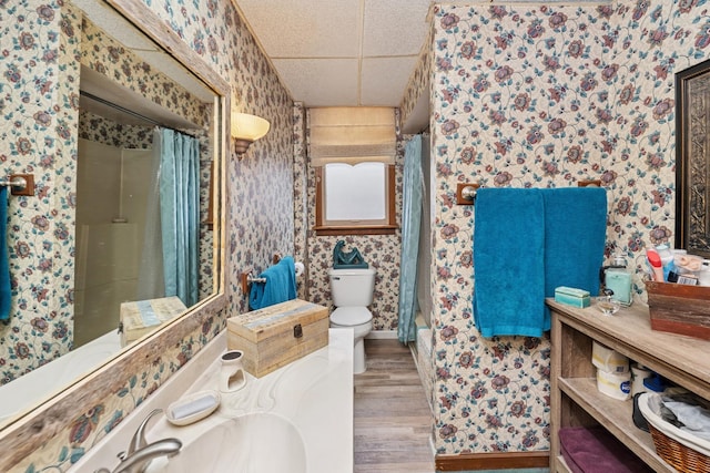 bathroom featuring a shower with shower curtain, a paneled ceiling, wood finished floors, and wallpapered walls