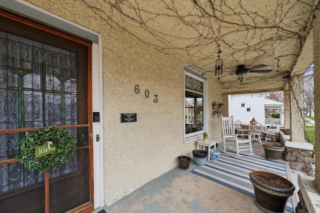 property entrance featuring a porch, stucco siding, and a ceiling fan