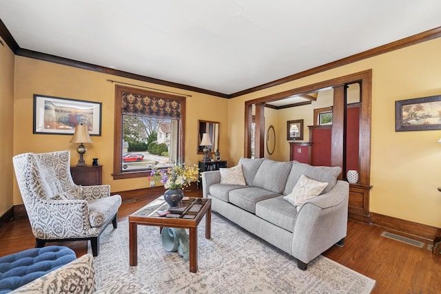 living room with crown molding, visible vents, baseboards, and wood finished floors