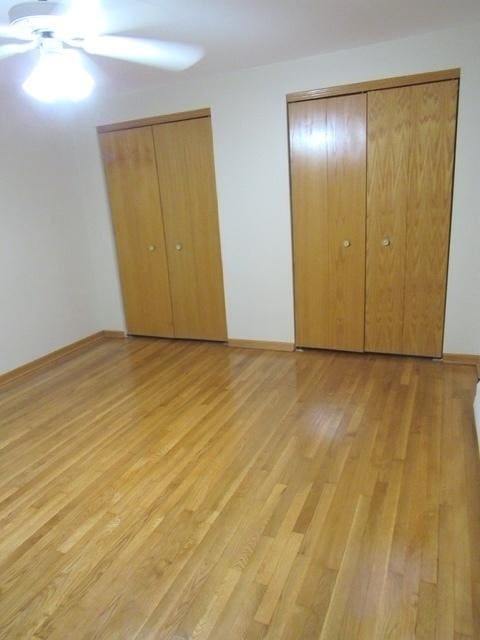 unfurnished bedroom with baseboards, light wood finished floors, and multiple closets