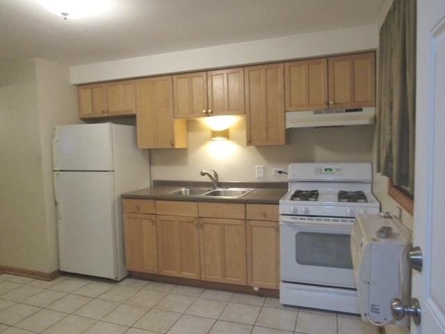 kitchen with light tile patterned floors, under cabinet range hood, white appliances, a sink, and dark countertops