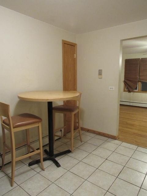 dining space with baseboards, a baseboard heating unit, and light tile patterned flooring