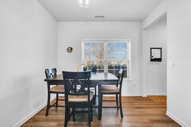 dining space featuring wood finished floors, visible vents, and baseboards