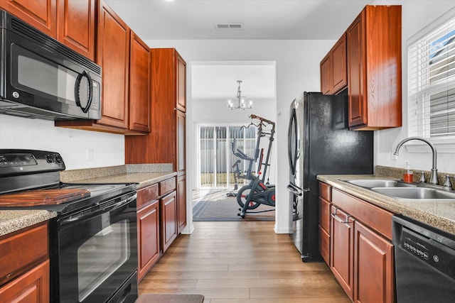 kitchen with visible vents, light countertops, light wood-style flooring, black appliances, and a sink