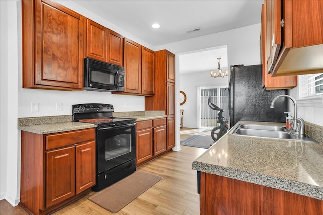 kitchen featuring visible vents, black appliances, light wood-style flooring, a sink, and recessed lighting