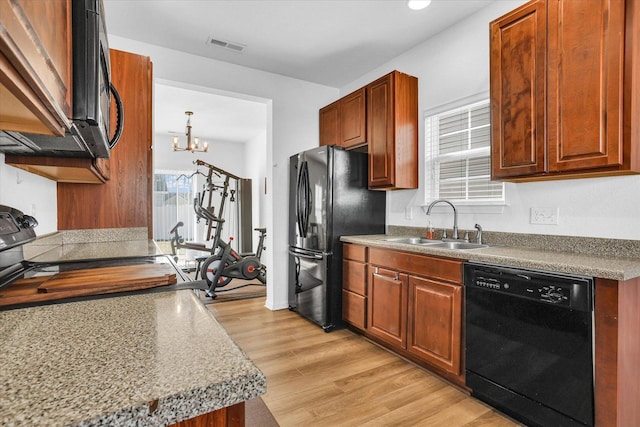 kitchen with a healthy amount of sunlight, black appliances, light wood-type flooring, and a sink