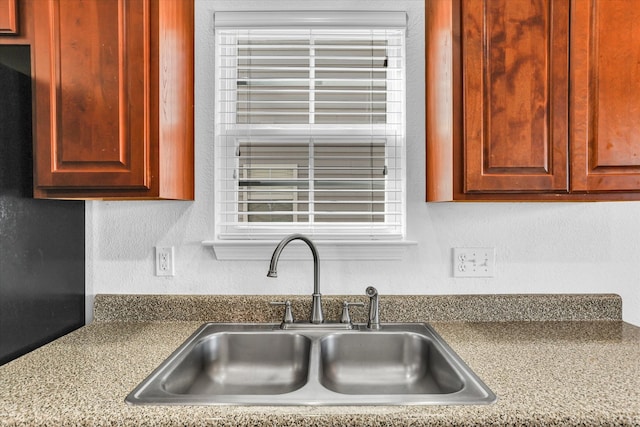 kitchen with a sink, reddish brown cabinets, and a textured wall