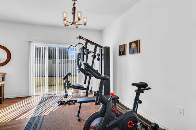 workout room featuring a notable chandelier, baseboards, and wood finished floors