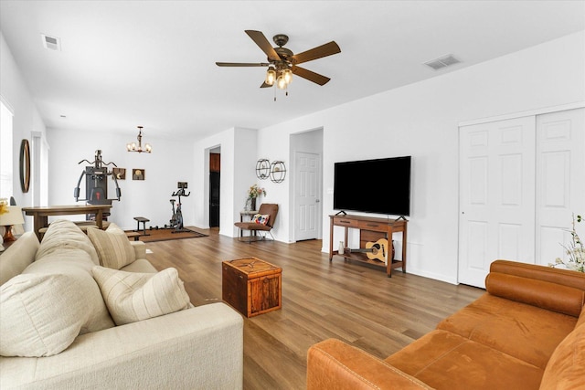 living room with visible vents, wood finished floors, and ceiling fan with notable chandelier