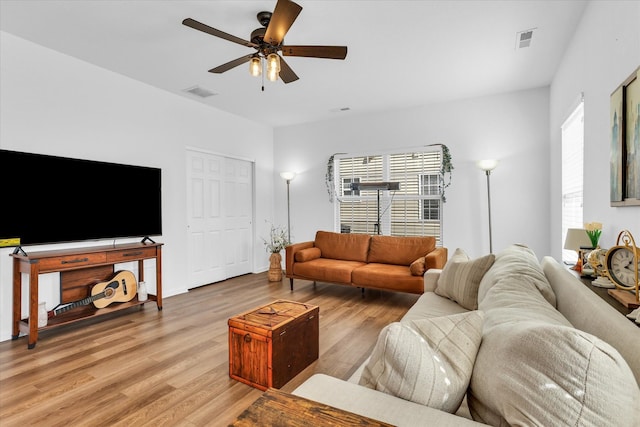 living room featuring visible vents, light wood-style flooring, and a ceiling fan