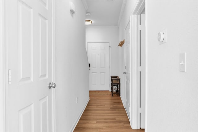 hallway featuring light wood-type flooring, baseboards, and ornamental molding