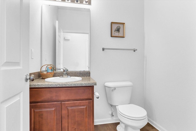 bathroom featuring toilet, vanity, baseboards, and wood finished floors