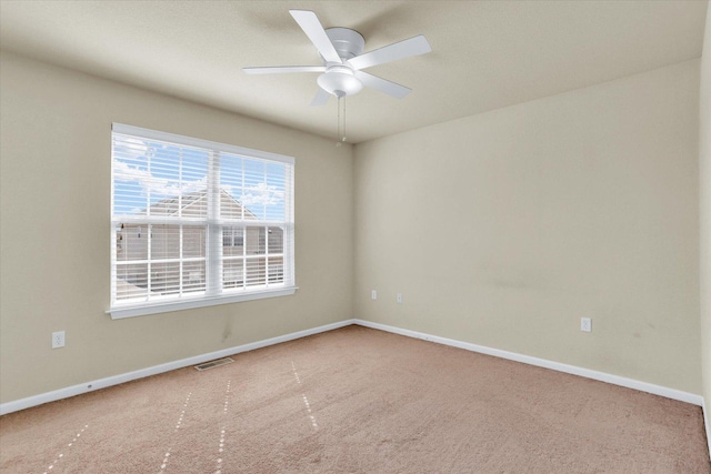 carpeted empty room with visible vents, a ceiling fan, and baseboards