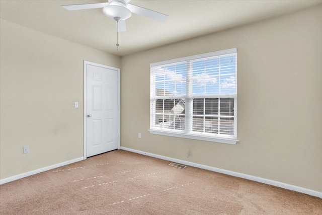 carpeted spare room with a ceiling fan, visible vents, and baseboards