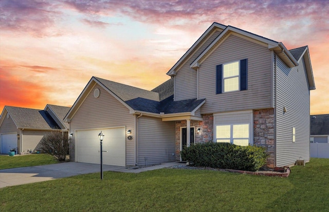 traditional-style home with stone siding, a garage, concrete driveway, and a yard