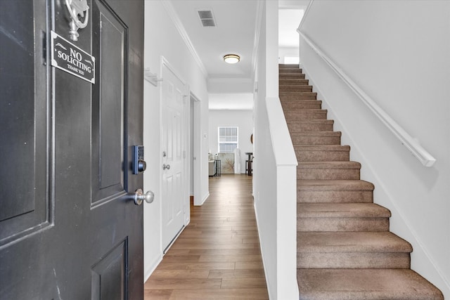 foyer entrance featuring stairs, crown molding, wood finished floors, and visible vents