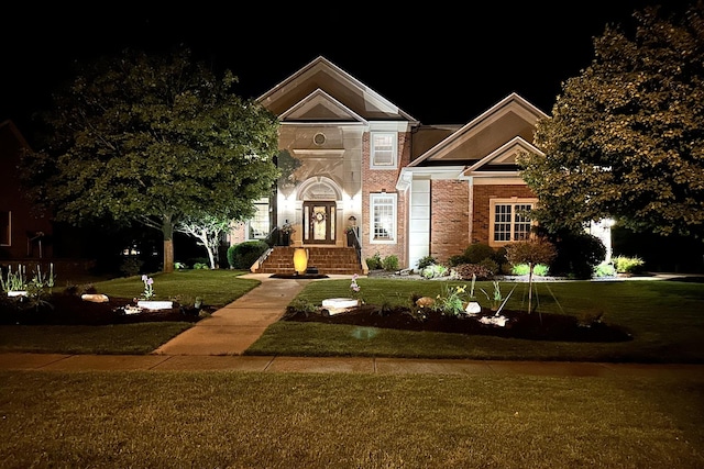 view of front facade with a yard and brick siding